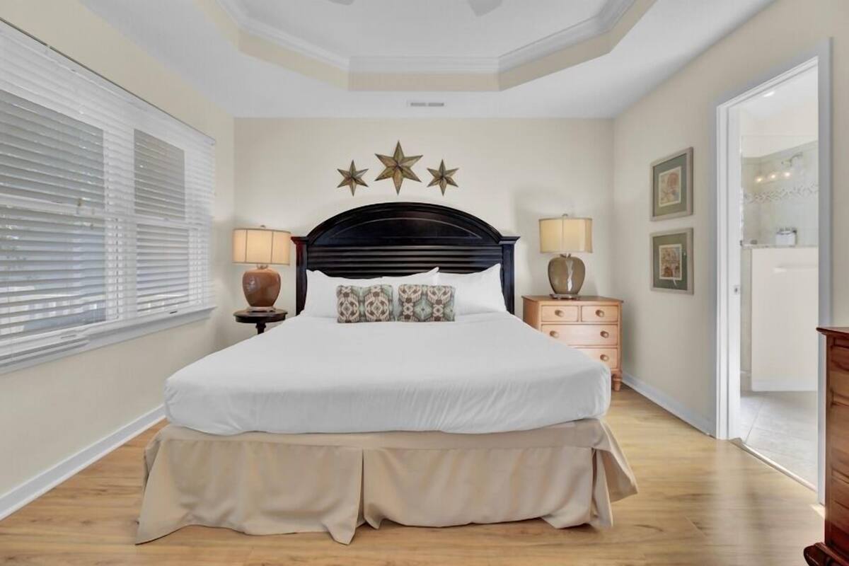 A bedroom with a large bed, bedside lamps, a dresser, and a ceiling with star decorations.
