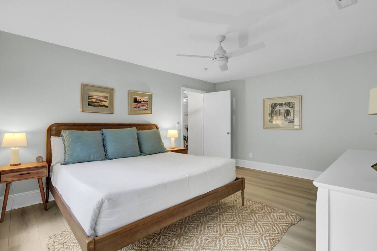 A bedroom with a wooden bed, a ceiling fan, and two bedside lamps.