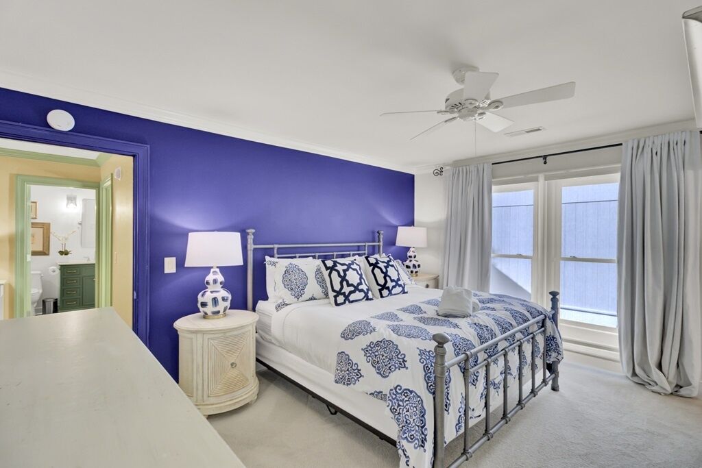 A bedroom with a bed, bedside tables, a ceiling fan, and a window with curtains.