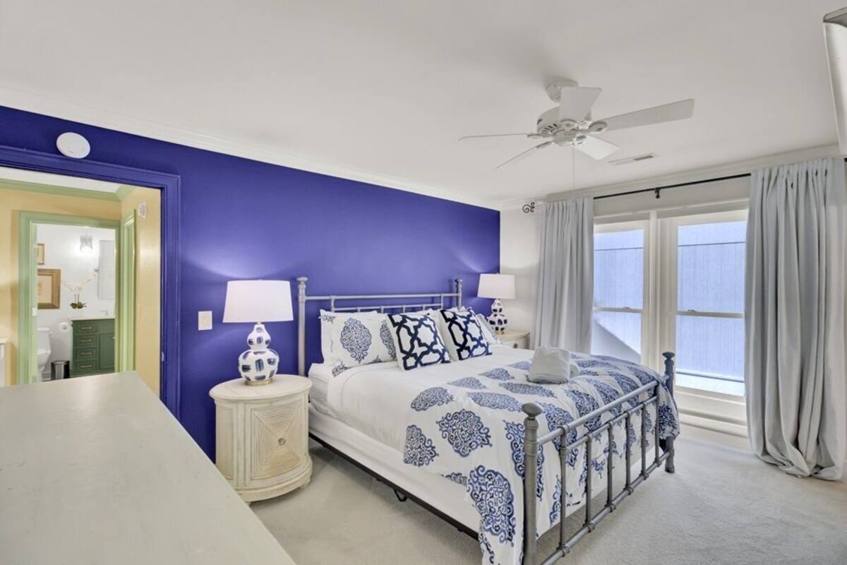 A bedroom with a bed, a nightstand, a ceiling fan, and a window with curtains.