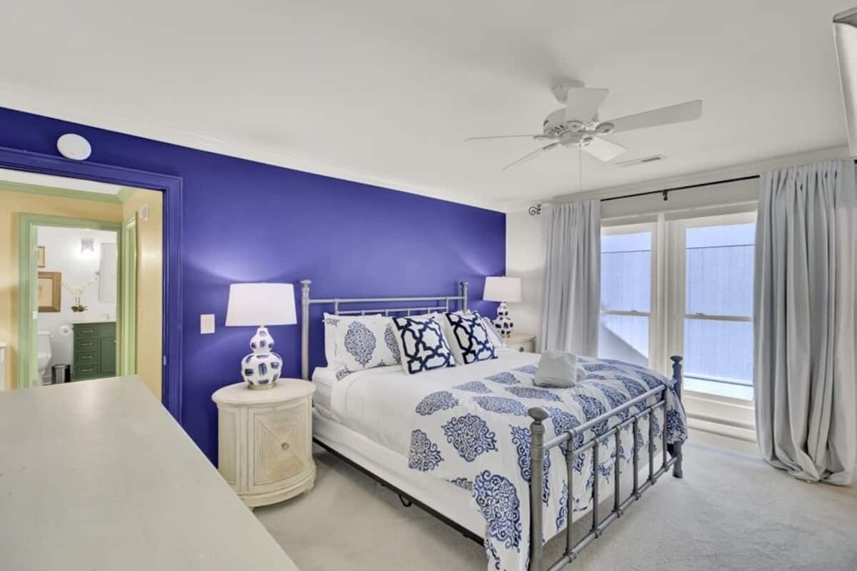 A bedroom with a bed, bedside tables, a ceiling fan, and a window with curtains.