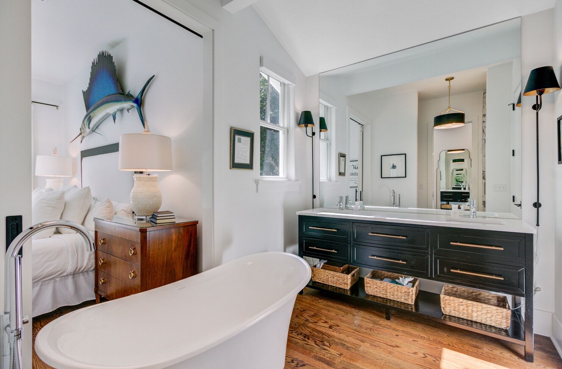 Un bagno moderno con una vasca da bagno freestanding, un mobile vanitario con uno specchio grande e una scultura a forma di pesce a parete.