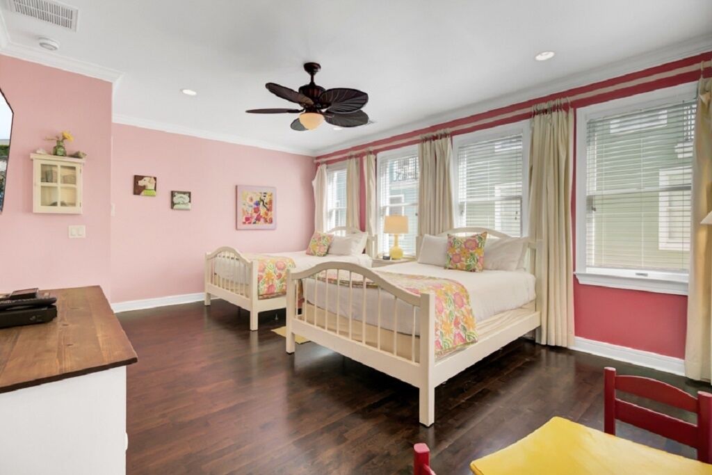 A bedroom with two single beds, a ceiling fan, a desk, and a chair.