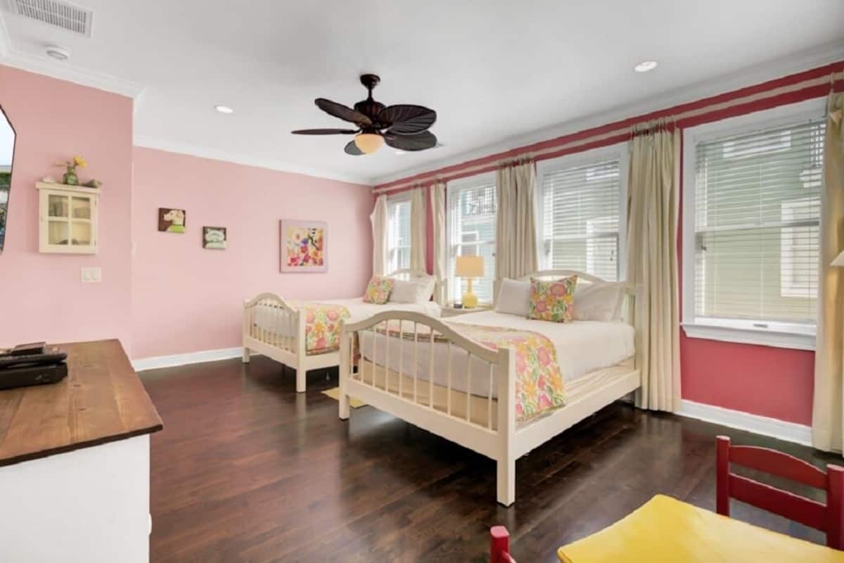 A bedroom with two single beds, a ceiling fan, a desk, and a chair.