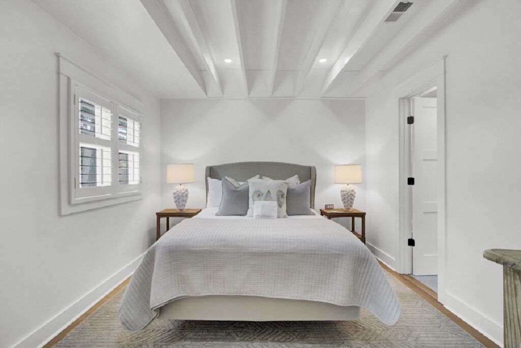A bedroom with a bed, nightstands, lamps, a window, and a door.