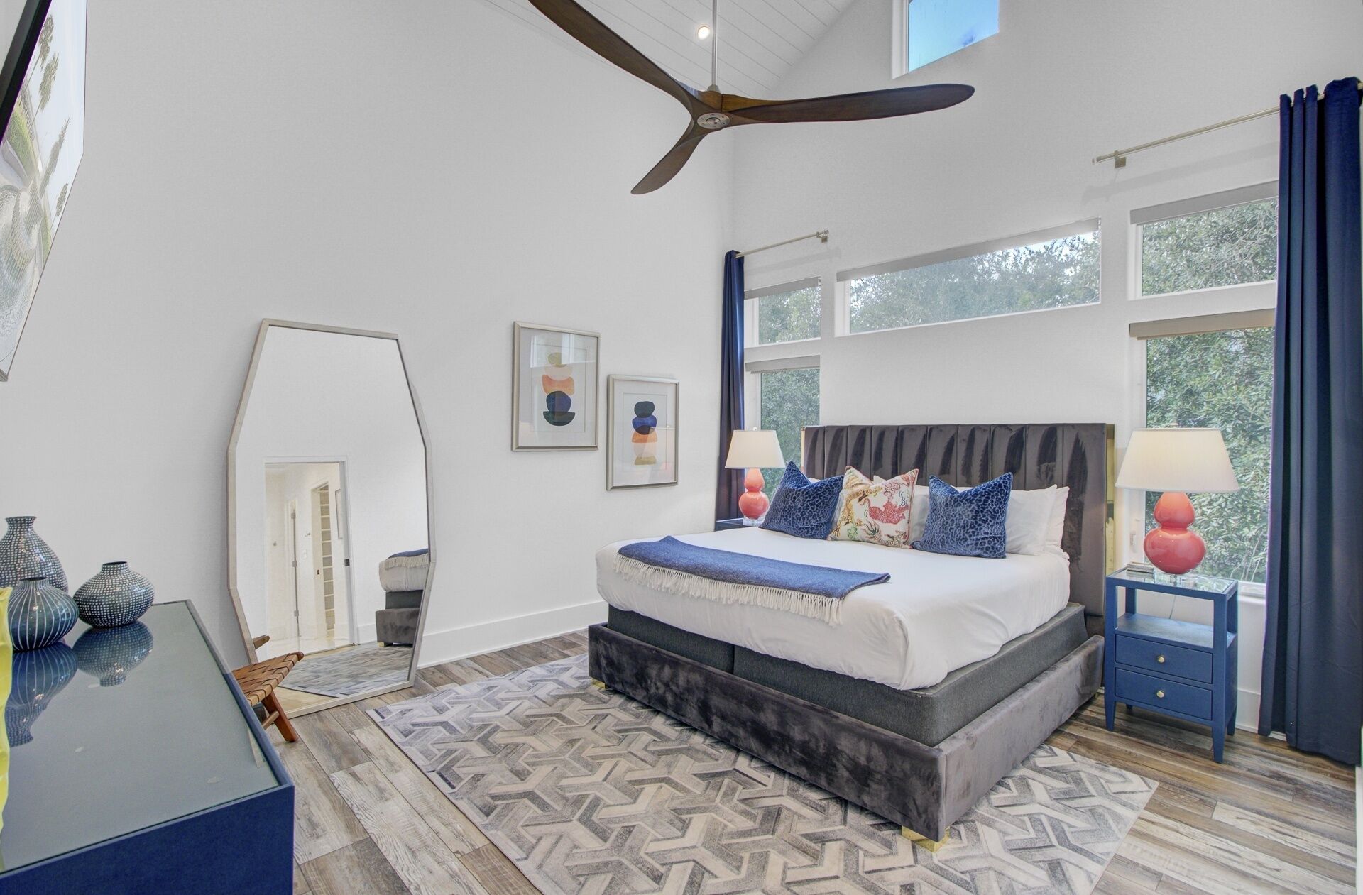 A bedroom with a bed, a ceiling fan, a window, and a nightstand.