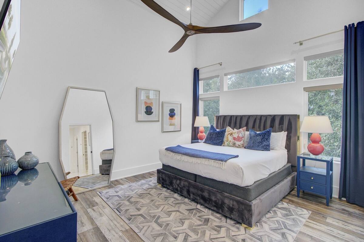 A bedroom with a bed, a ceiling fan, a window, and a nightstand.
