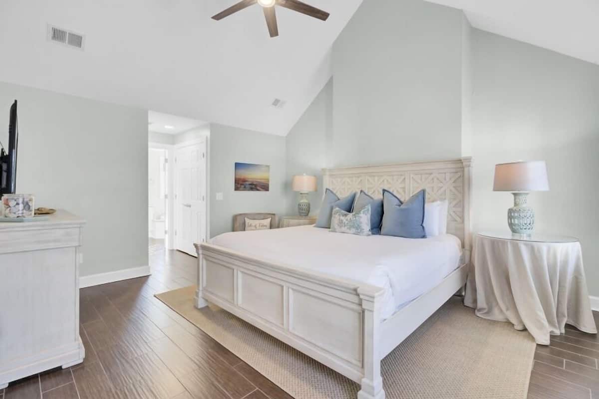 A bedroom with a large bed, a ceiling fan, a nightstand, and a lamp.