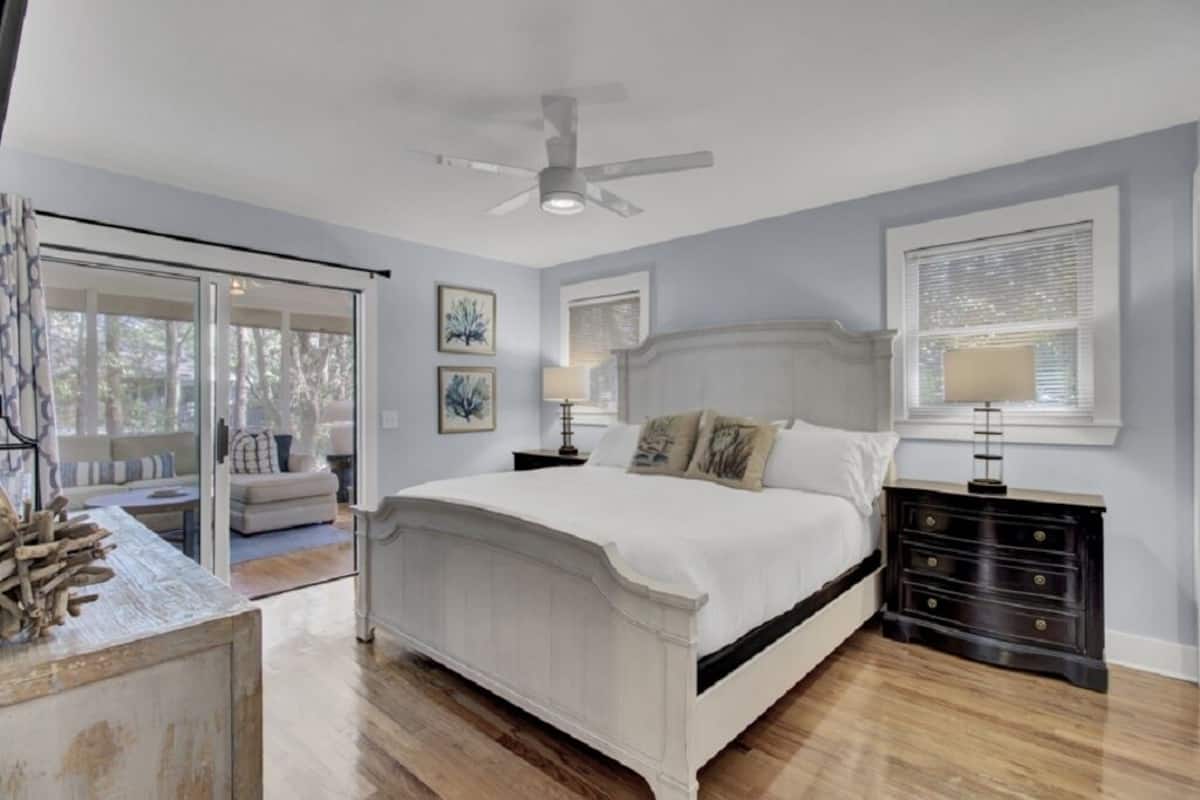 A bedroom with a bed, a nightstand, a ceiling fan, and a window with blinds.