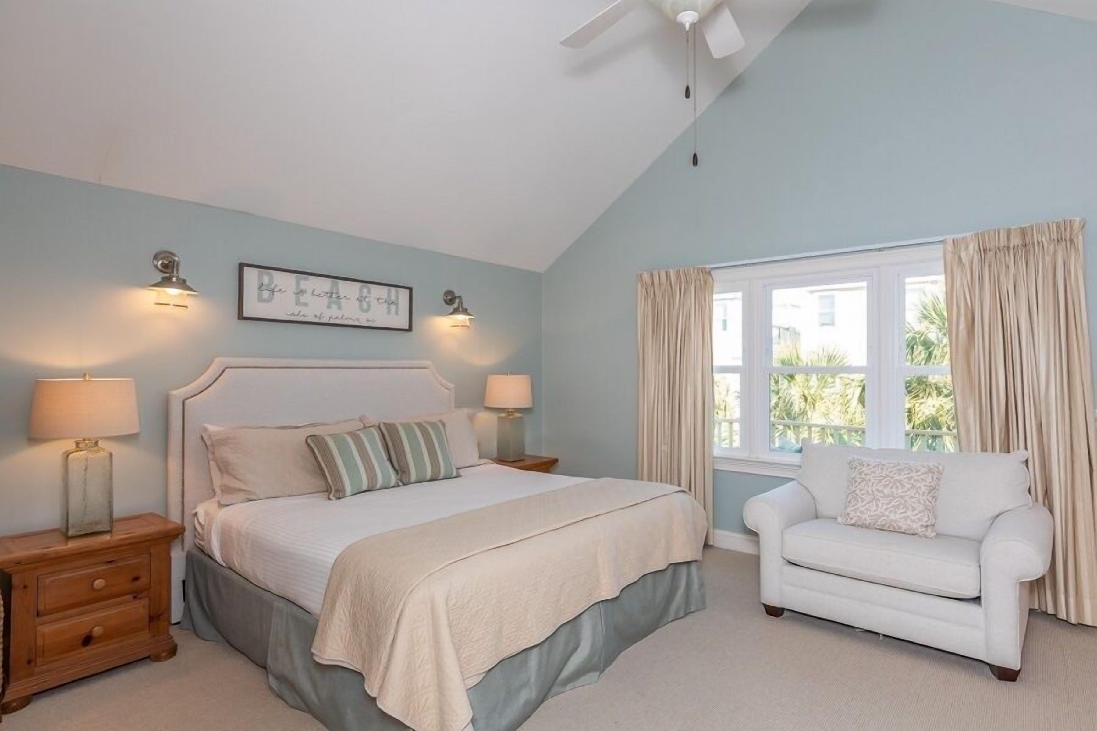 A bedroom with a bed, bedside tables, a nightstand, a window with curtains, and a chair.