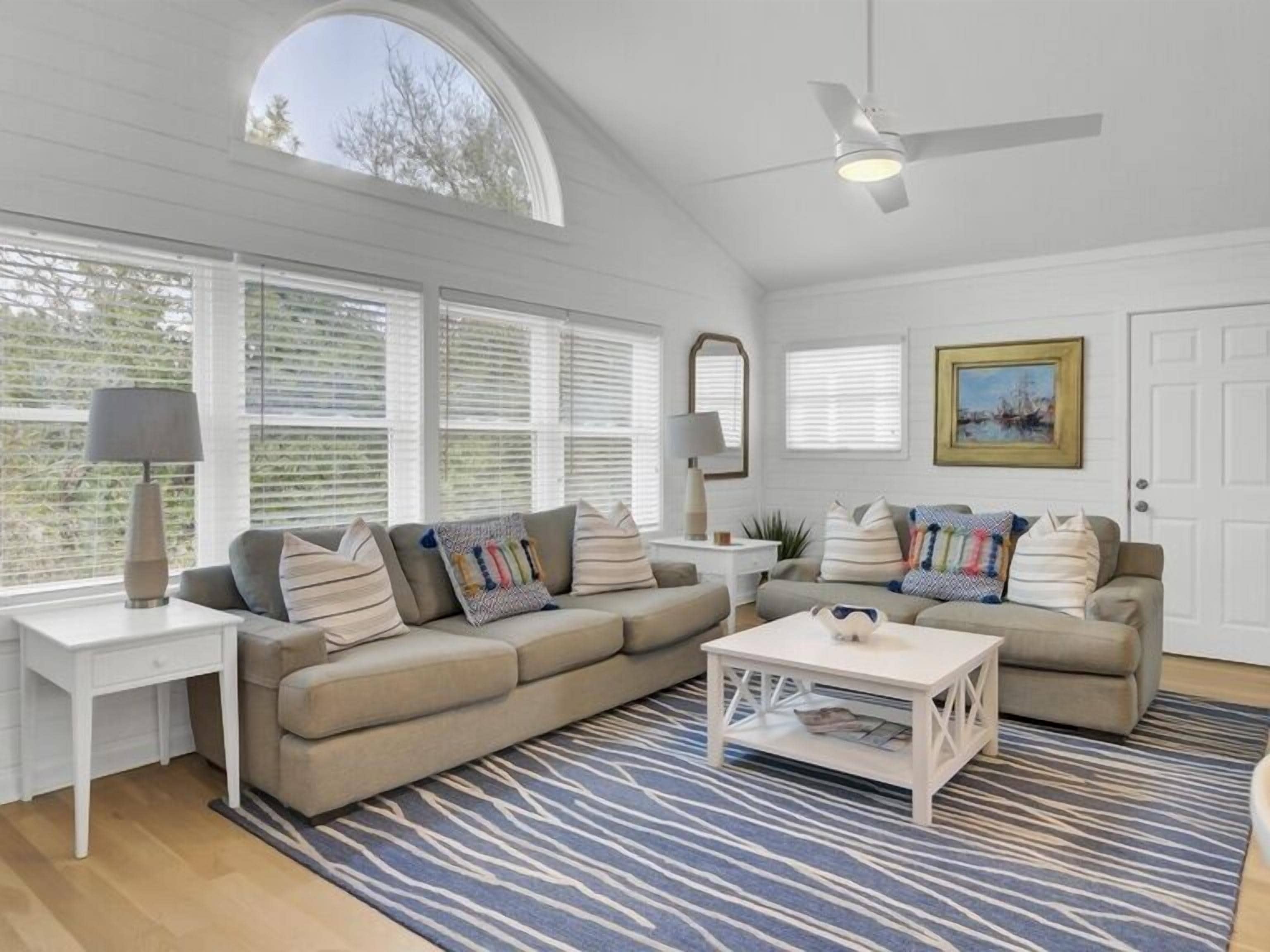 A spacious living room with two sofas, a coffee table, and a ceiling fan.