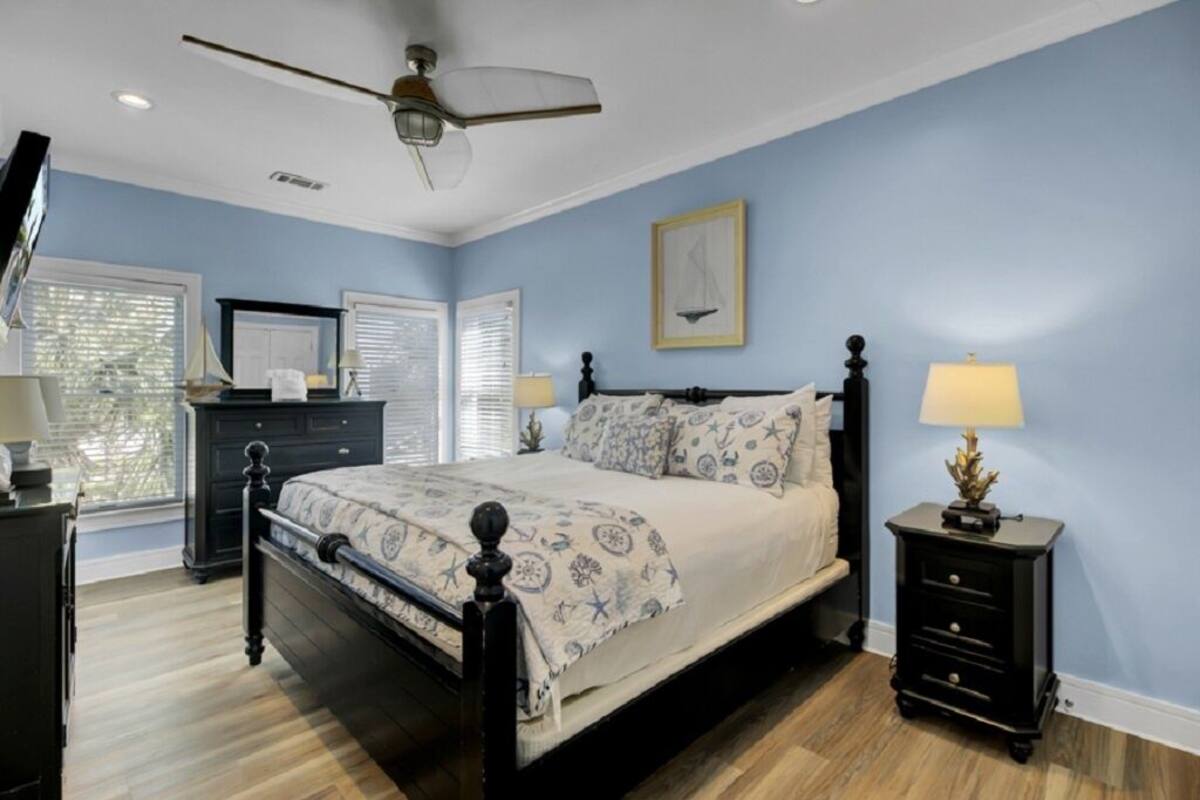 A bedroom with a bed, bedside tables, a ceiling fan, and a window with blinds.