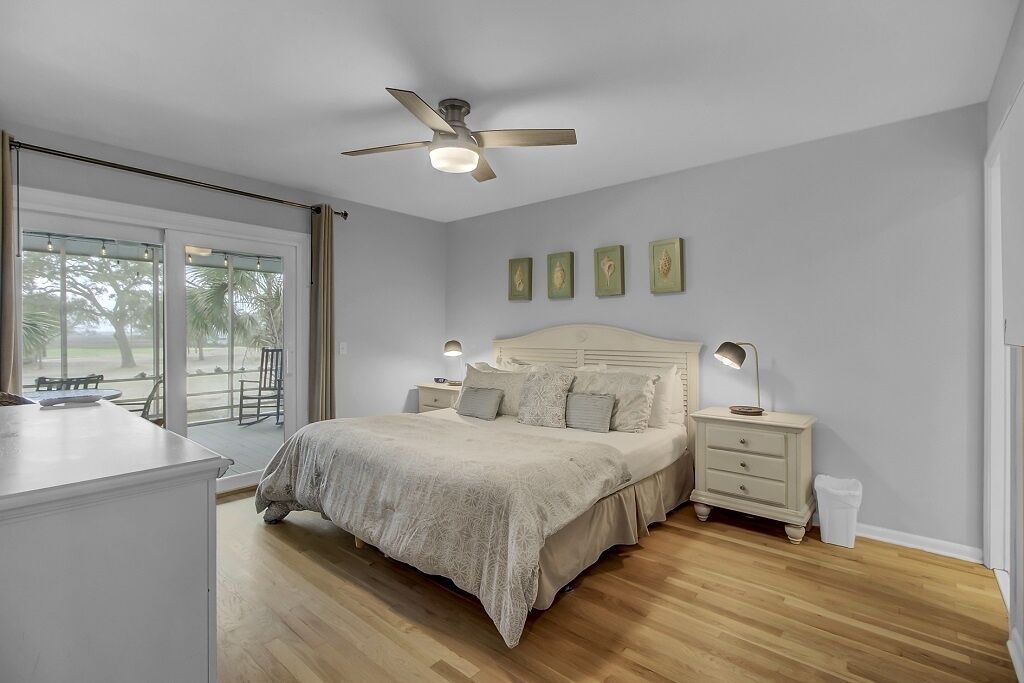 A bedroom with a bed, bedside tables, a ceiling fan, and a view through a sliding door.