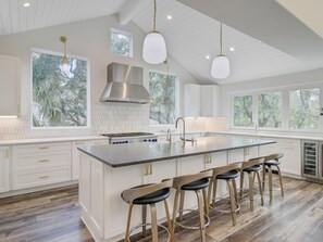 A modern kitchen with a large island, bar stools, and pendant lighting. - Wild Dunes Vacation Homes 3&4 Bedrooms (Isle of Palms)