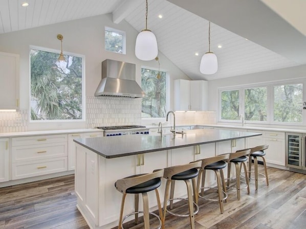 A modern kitchen with a large island, bar stools, and pendant lighting. - Wild Dunes Vacation Homes 3&4 Bedrooms (Isle of Palms)