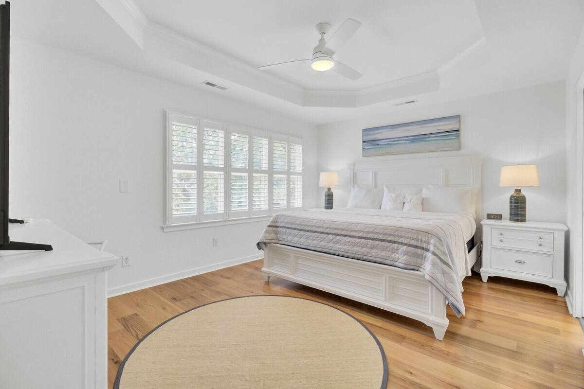 A bedroom with a bed, bedside tables, a ceiling fan, and a window with blinds.
