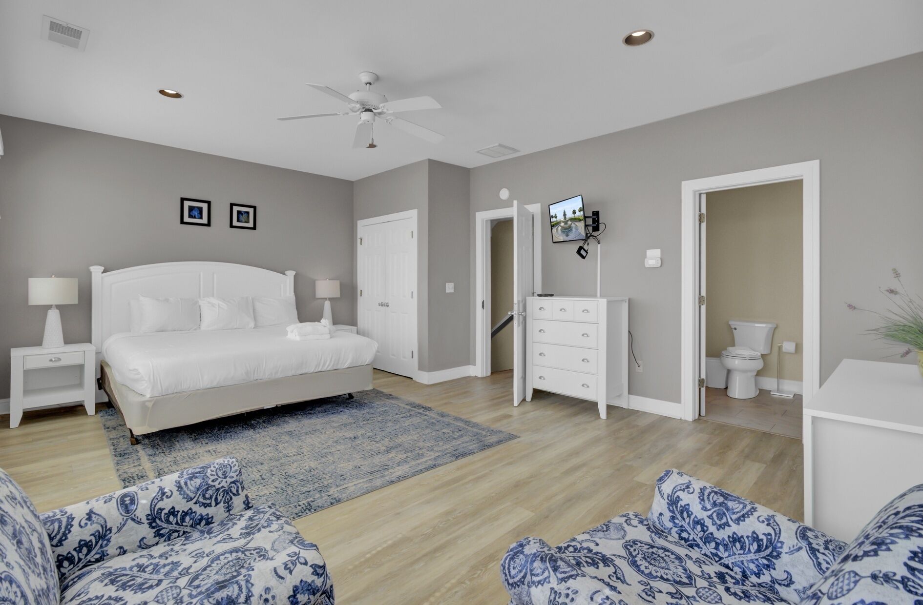 A bedroom with a bed, nightstands, a dresser, a TV, and a bathroom.