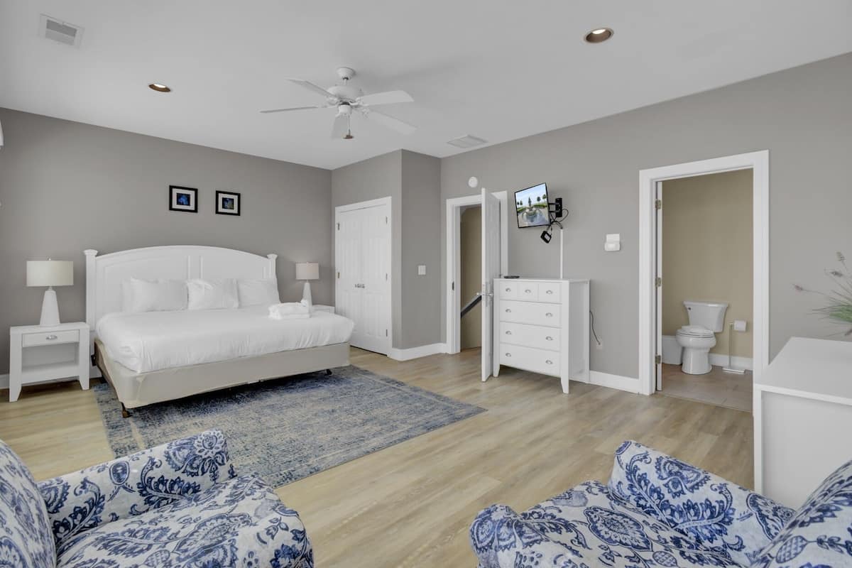 A bedroom with a bed, nightstands, a dresser, a TV, and a bathroom.