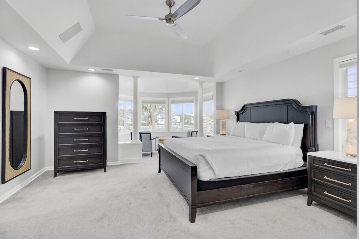 Ein Schlafzimmer mit einem großen Bett, einem Schminktisch, einem Spiegel und einem Deckenventilator.