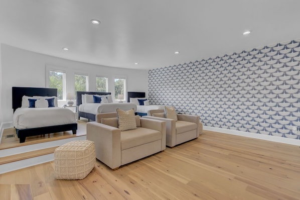 Ein modernes Schlafzimmer mit zwei Betten, einer Sofagarnitur, einer Wand mit Muster und Holzboden.