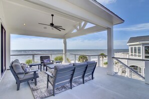 A covered outdoor area with a ceiling fan, seating, and a view of the ocean. - Wild Dunes Vacation Homes 5-7 Bedrooms (Isle of Palms)