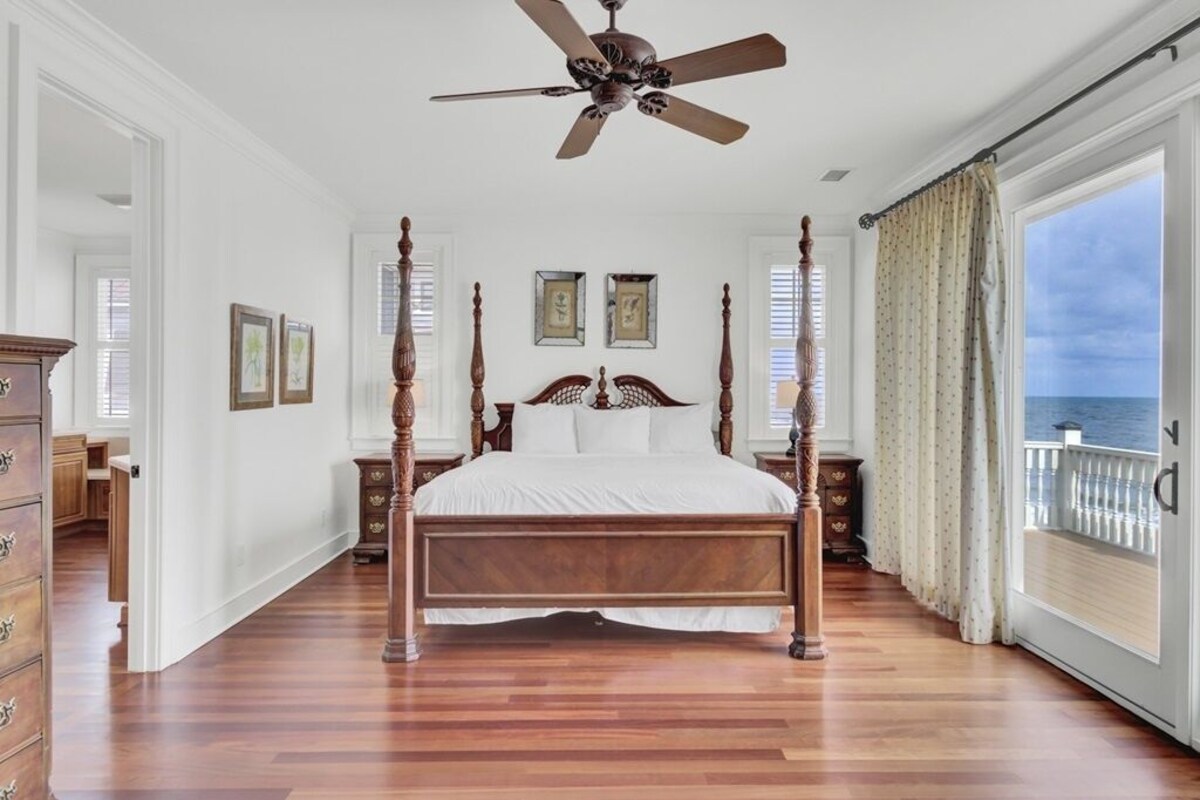 Ein Schlafzimmer mit Himmelbett, Deckenventilator und Meerblick.