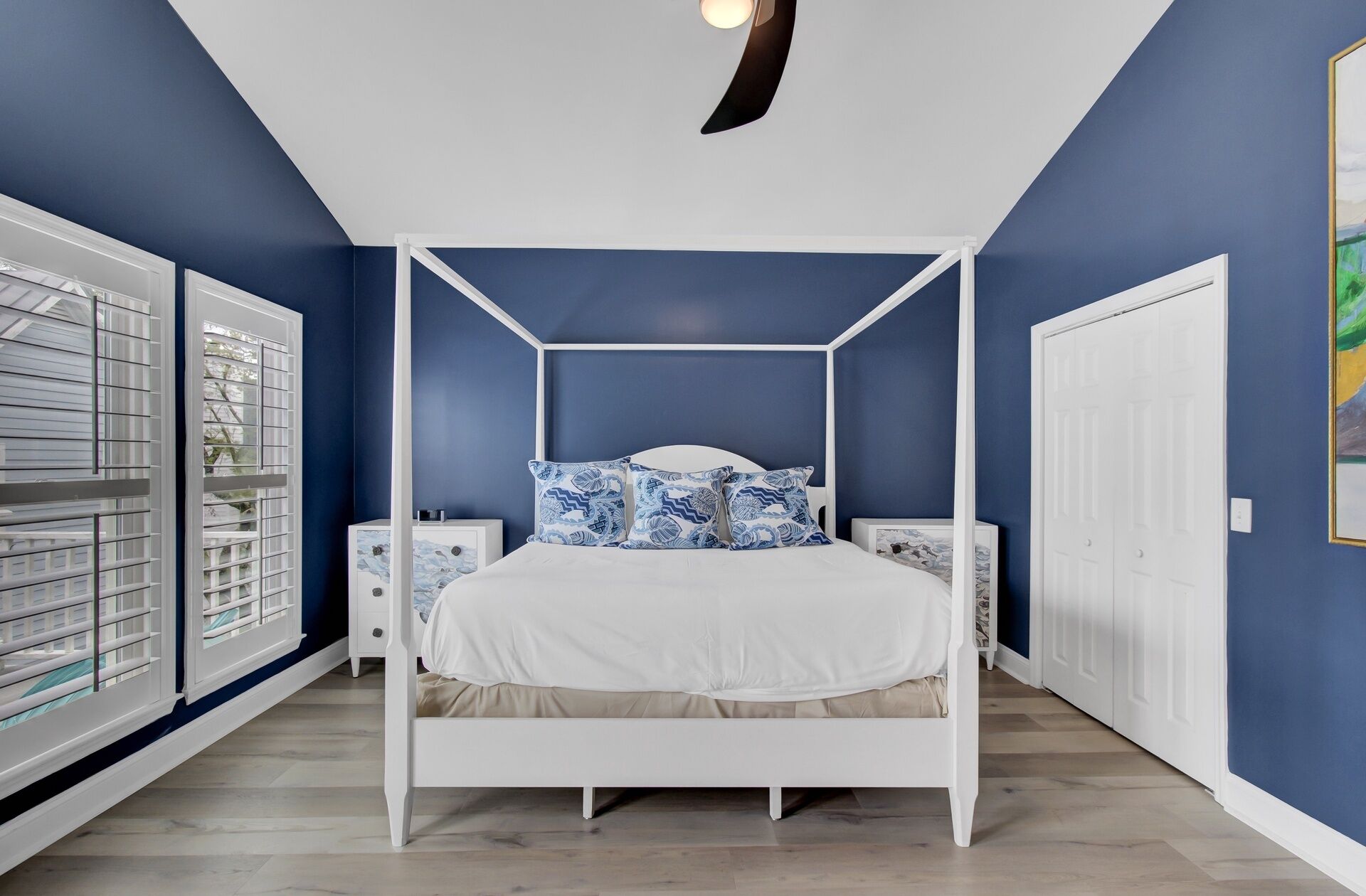 Ein Schlafzimmer mit einem Himmelbett, weißen Nachttischen und einem weißen Kleiderschrank.
