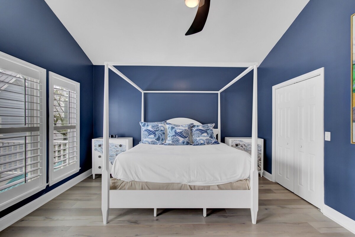 Ein Schlafzimmer mit einem Himmelbett, weißen Nachttischen und einem weißen Kleiderschrank.