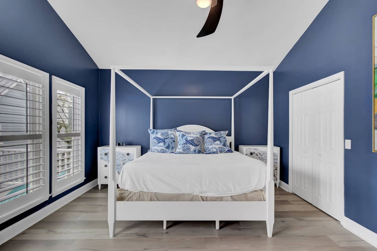 Ein Schlafzimmer mit einem Himmelbett, weißen Nachttischen und einem weißen Kleiderschrank.