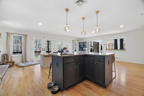 A spacious kitchen with a large island, pendant lighting, and a view of the outdoors. - The Rail & Pine Spacious Masthope Mountain Retreat (Lackawaxen)
