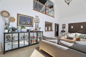 A spacious living room with a high ceiling, a glass cabinet with decorative items, a sofa, and a chessboard. - The Rail & Pine Spacious Masthope Mountain Retreat (Lackawaxen)