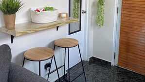 A reception area with a wooden bench, a small table with a basket, a mirror, and a door with a sign. - Private Mini Villa w/ Pool, Terrace, BBQ & Secure Parking in Ponce (Ponce)