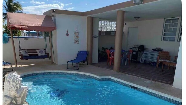 A swimming pool with a stone wall and a metal ladder. - Private Mini Villa w/ Pool, Terrace, BBQ & Secure Parking in Ponce (Ponce)