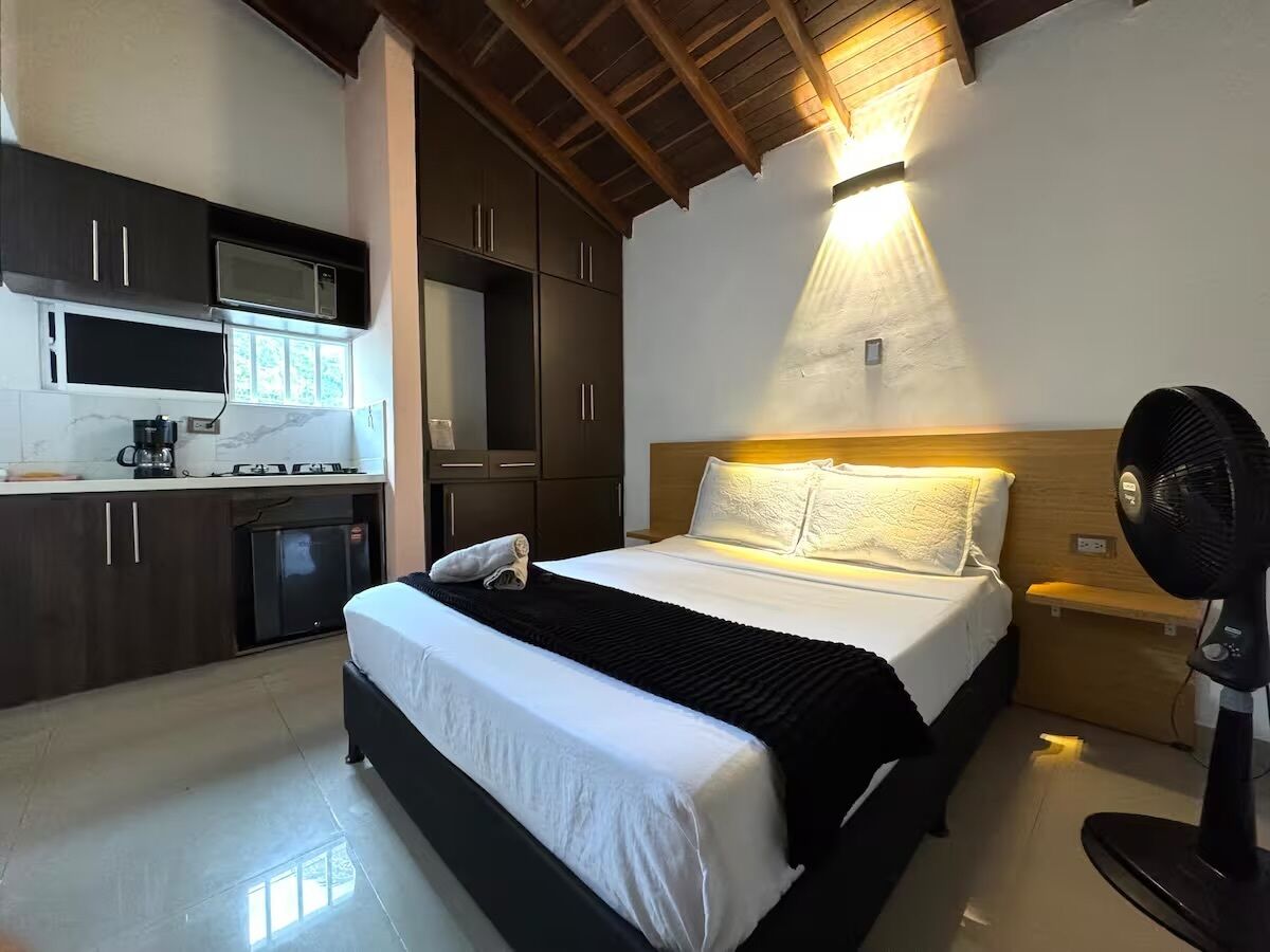 A bedroom with a bed, bedside table, and a fan.