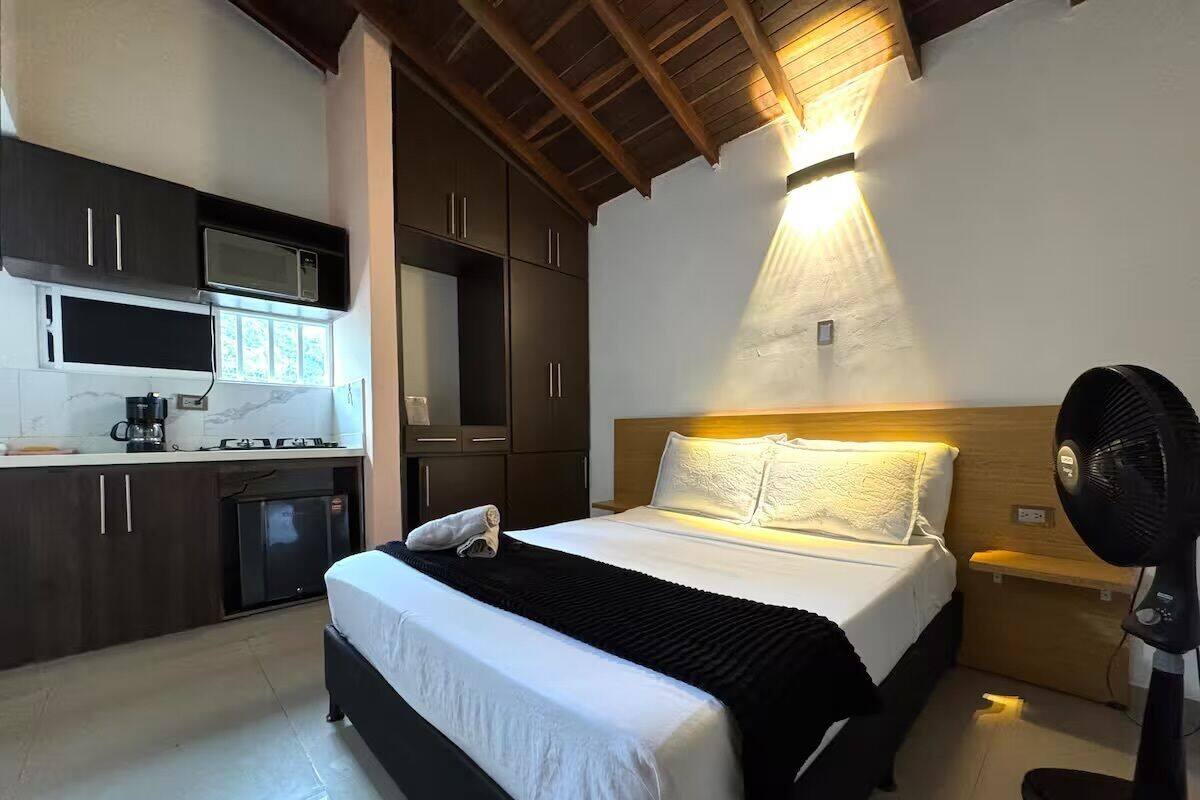 A bedroom with a bed, bedside table, and a fan.