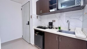 Una cocina compacta con estufa a gas, cafetera, microondas y pileta.