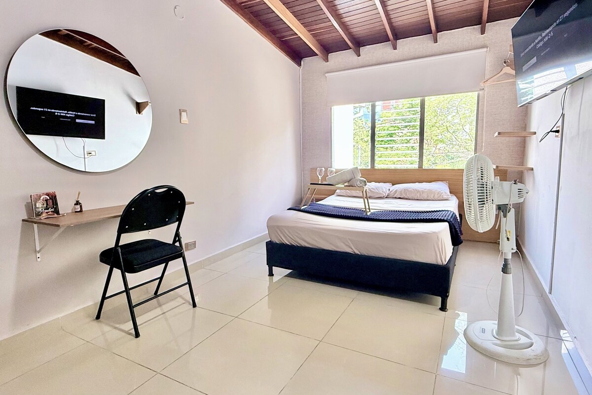 Quarto com uma cama, uma cadeira, uma TV e uma janela.