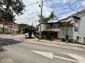 A residential street with a white building, a red door, and a person skateboarding. - Apartaloft Laureles Medellín (Medellín)