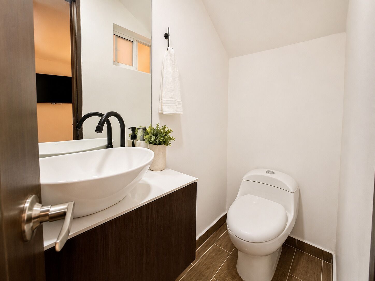 A modern bathroom with a white sink, black faucet, and a white toilet.