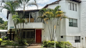 Un edificio de dos pisos con una puerta roja, varias ventanas y un balcón.