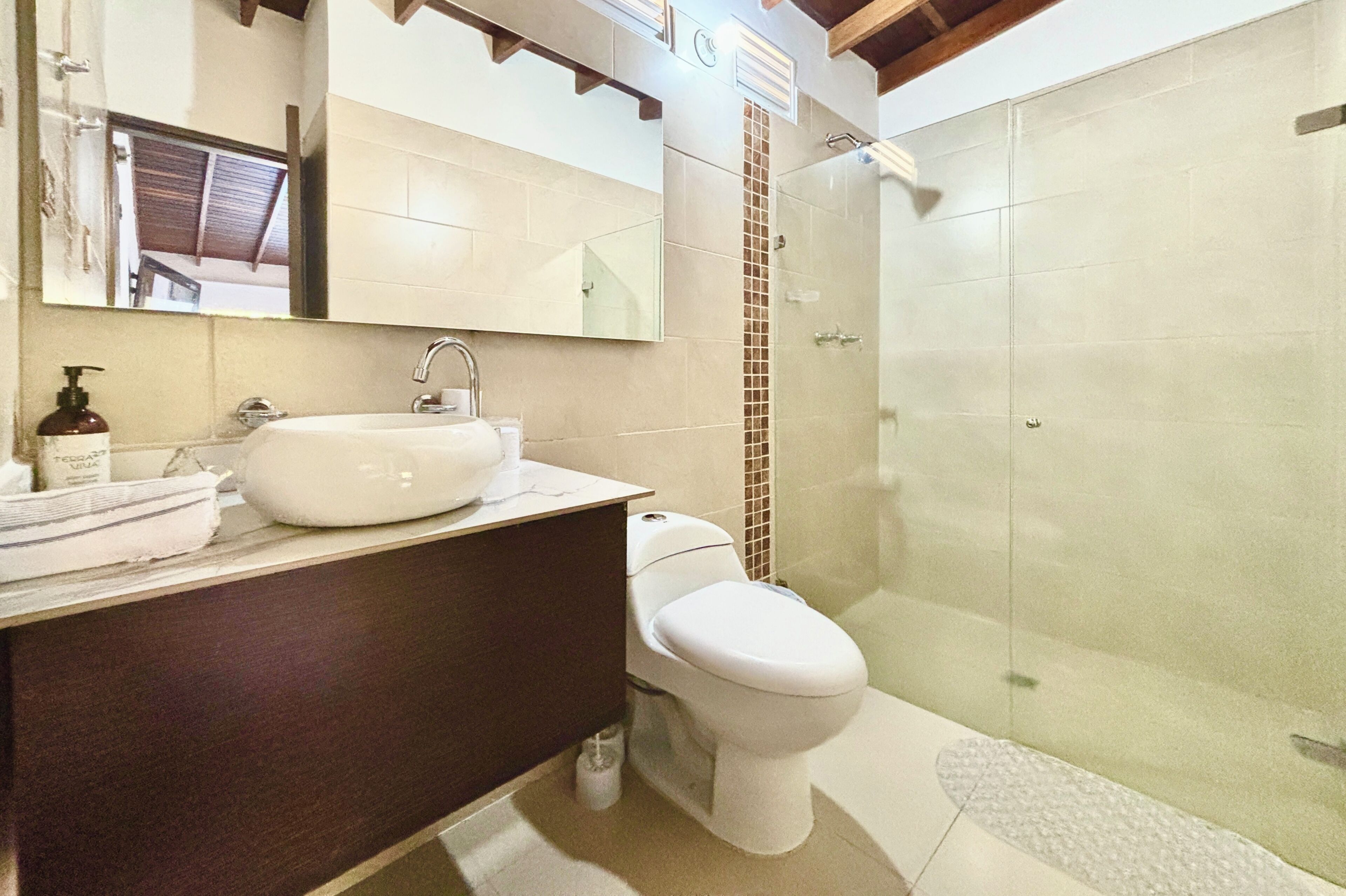 A bathroom with a sink, mirror, toilet, and shower.