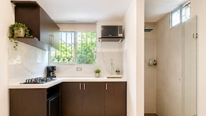 Una cocina moderna con armarios de madera oscura, una estufa a gas y una ventana con vistas a la vegetación.