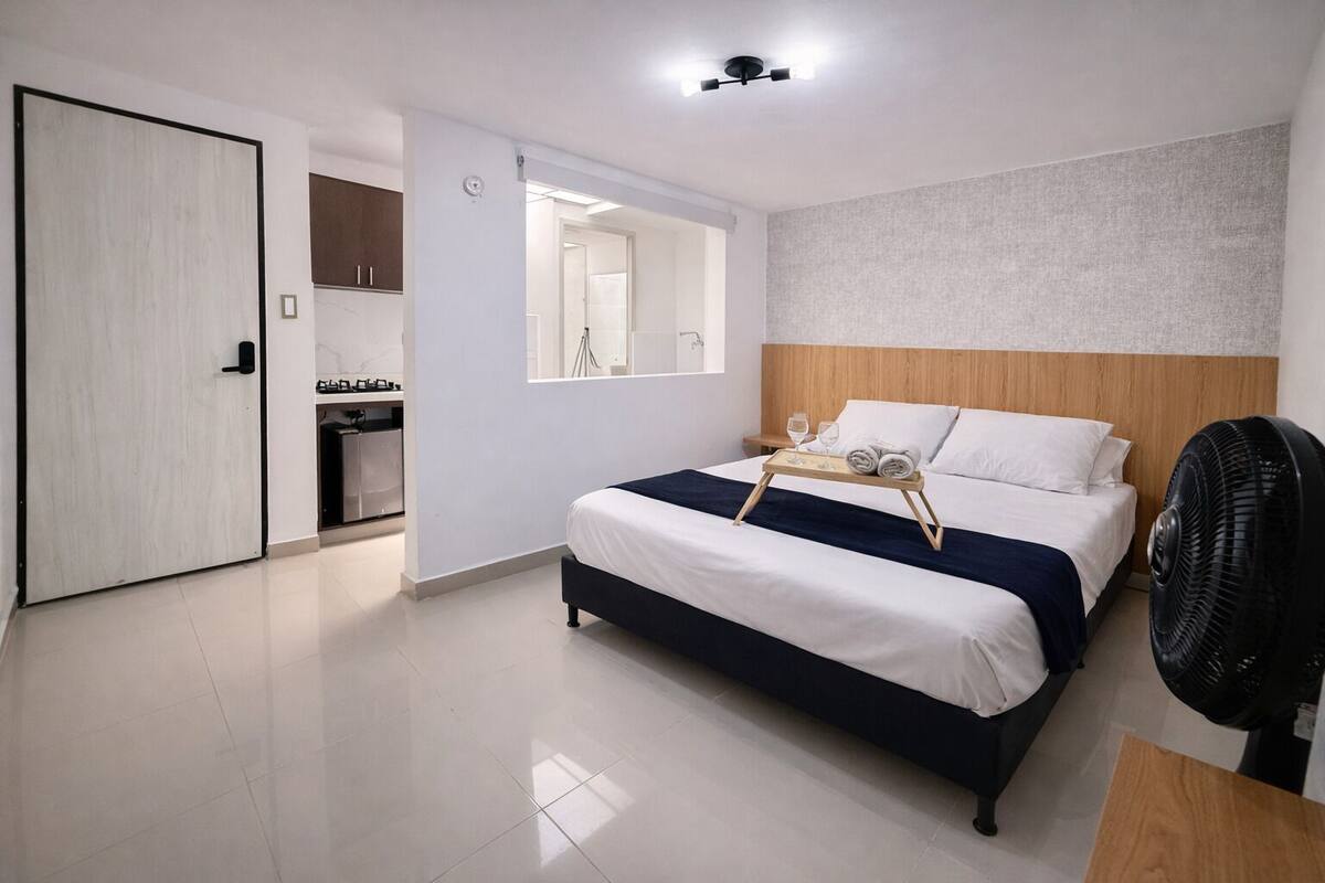 A bedroom with a bed, bedside table, and a fan.