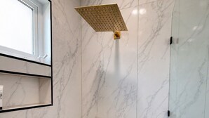 A modern bathroom with a shower, marble walls, and a window. - Standard plus room 207 9 minutes from Val'Quirico (Tetlatlahuca)
