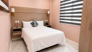 A bedroom with a bed, nightstands, a headboard, a wardrobe, and a window with blinds. - Standard plus room 207 9 minutes from Val'Quirico (Tetlatlahuca)