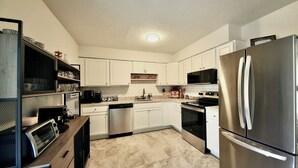 A modern kitchen with white cabinets, stainless steel appliances, and a tiled floor. - Family-Friendly Covington Escape w/ Fenced Backyard, Full Kitchen & Coffee Bar (Covington)
