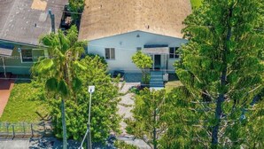 A single-story building with a sloped roof, surrounded by greenery and a paved driveway. - Fantastic 1-bedroom townhome with AC in vibrant Miami (Miami)