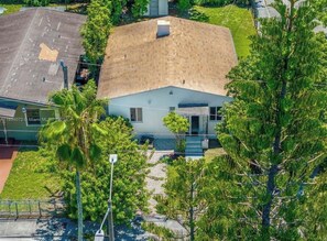 A single-story building with a sloped roof, surrounded by greenery and a paved driveway.