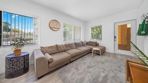 A modern living room with a beige sectional sofa, a round side table, and a small wooden stool. - Fantastic 1-bedroom townhome with AC in vibrant Miami (Miami)