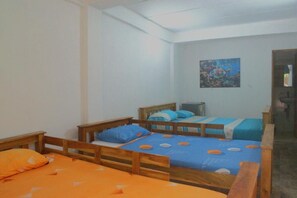 A room with three wooden beds, each with a blue and orange bedspread. There is a painting on the wall above the beds. - MANGO TREE ISLAND 420 (Cartagena)